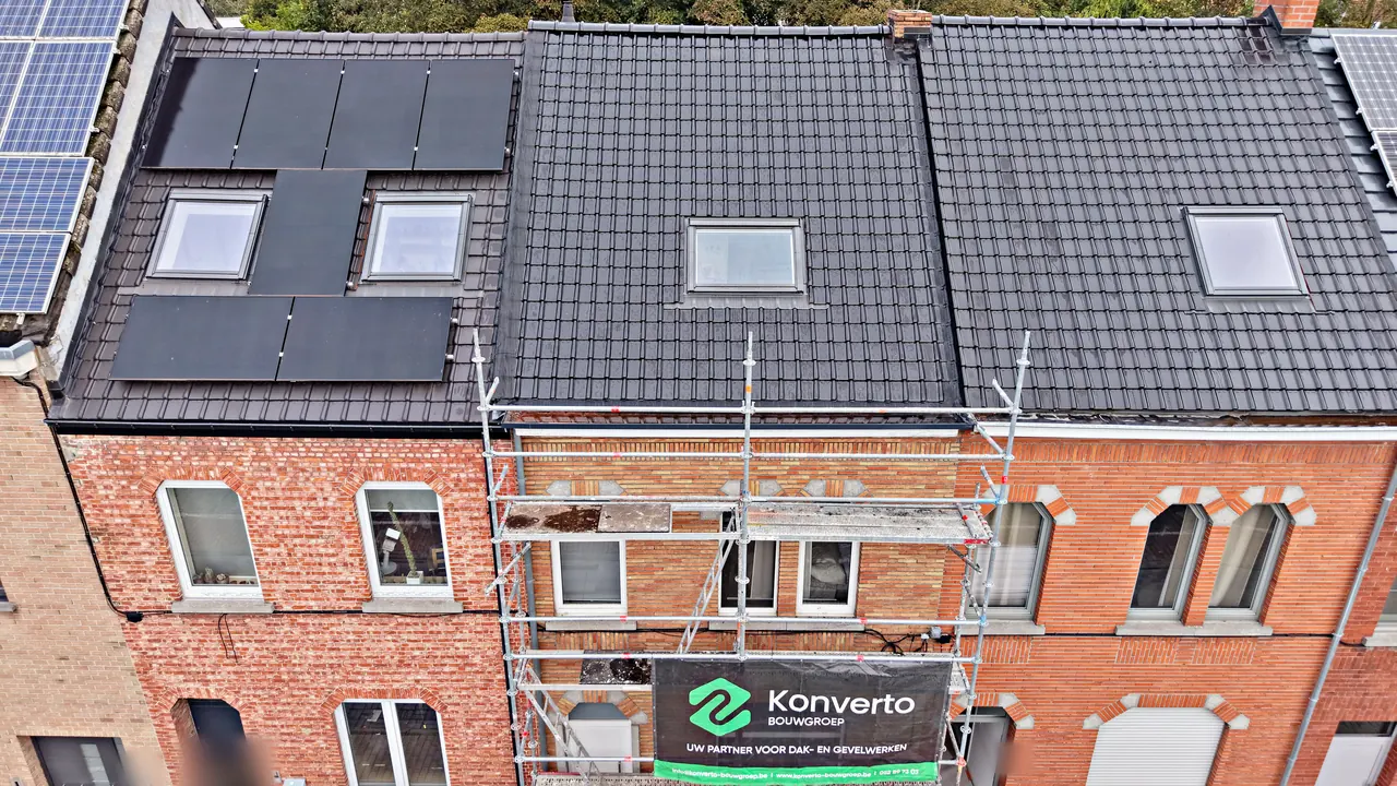 Dakrenovatie in Aalst: het voorste dakvlak van een rijwoning met donkere pannen en een dakraam, met stelling en spandoek van Konverto